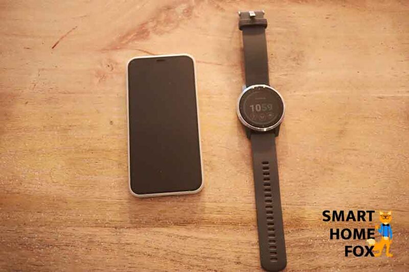 Man sieht die Garmin vivoactive 4 neben einem Handy auf dem Tisch liegen.